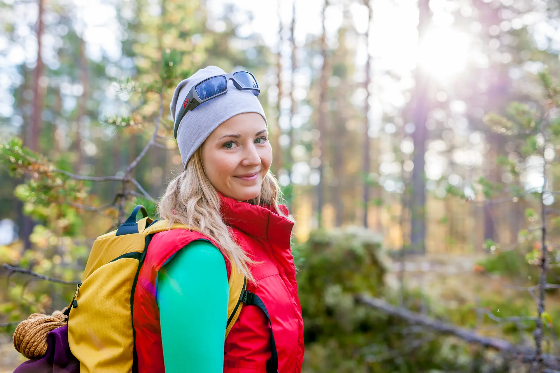 Nainen retkeilee ja hymyilee metsässä