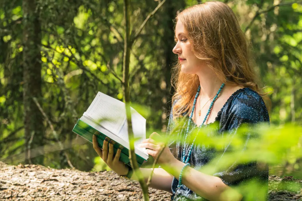 Nainen lukee kirjaa metsässä - Terveyspsykologia, itsenäiset opinnot